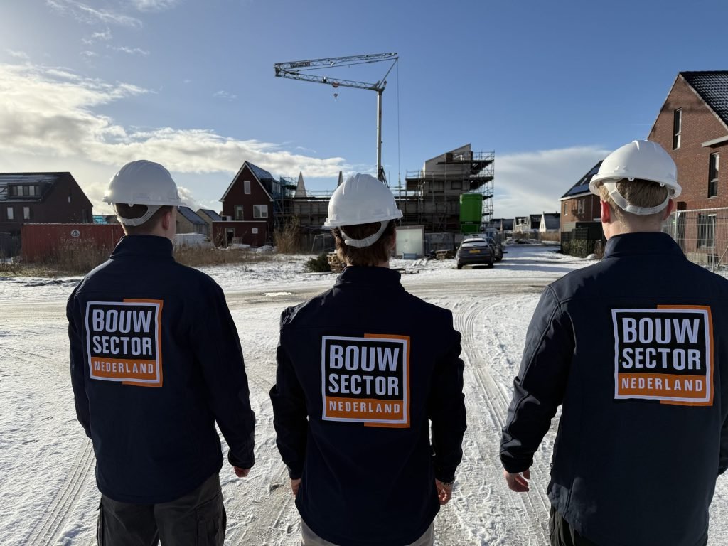 Drie mannen van Bouwsector Nederland met helm van achteren gezien voor nieuwe huizen en een bouwkraan